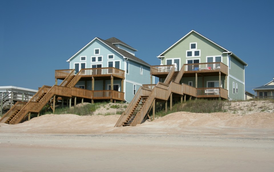 How to create the perfect family vacation home: tips and considerations Beachfront family vacation home with elevated wooden decks overlooking the ocean.