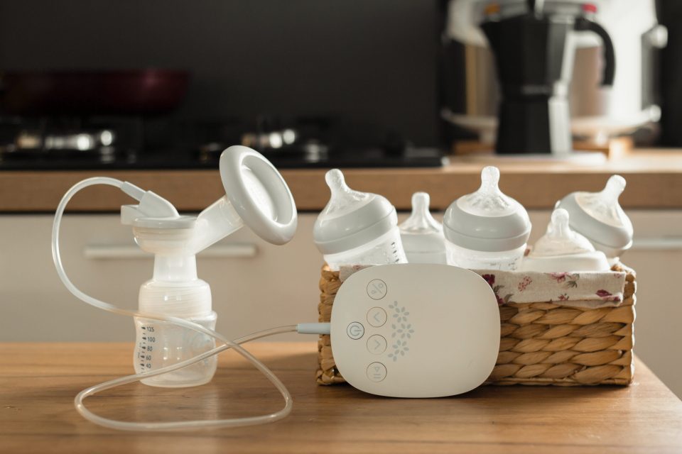 How often should i pump and breastfeed? A quick guide for new moms  Electric breast pump and bottles for breasting milk in a wicker basket on a wooden table