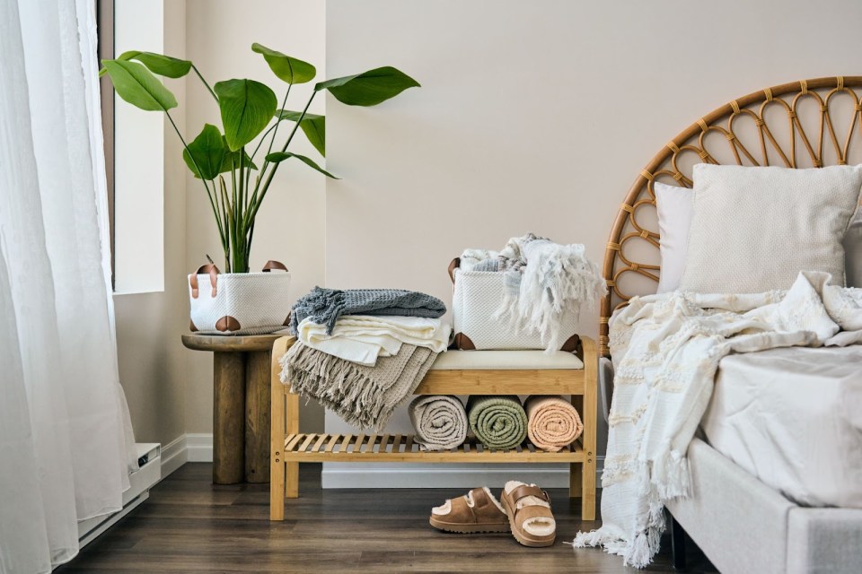 Upgrade your sleep experience with the perfect sheet sets A cozy, modern bedroom features a wood bench stacked with soft, neutral-colored sheet sets and throws, highlighting the perfect sheet sets for comfort and style.