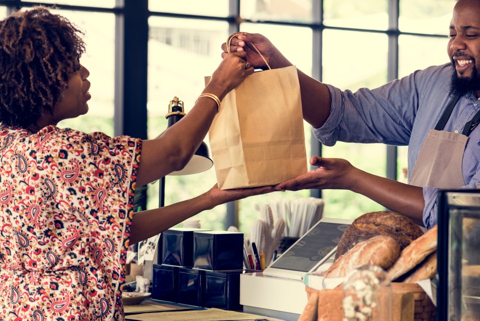 Buy black everything: a movement for now and beyond An african american woman making a purchase at a black business to buy black everything for the #buyblackmovement