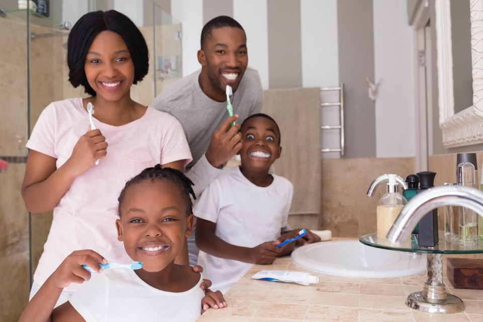 An african american family brushes their teeth together for an article on why every family needs a trusted family dentist