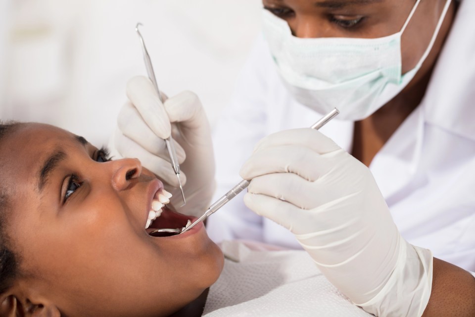 An african american dentist works on the mouth of an african american girl for an article on why every family needs a trusted family dentist
