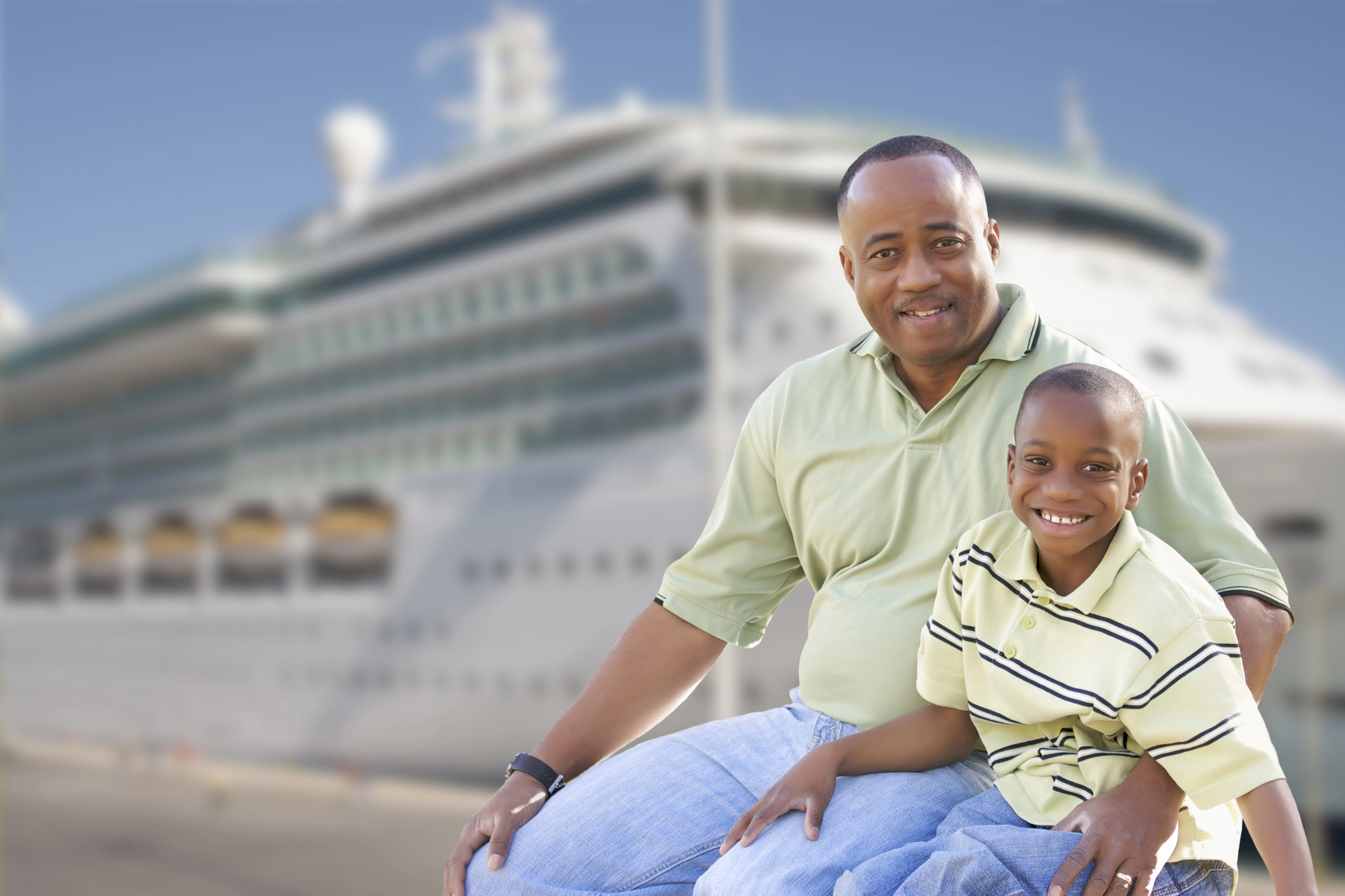 10 tips for traveling with a child with autism Black father and son smiling together in front of cruise ship, representing joyful travel moments with a child with autism – traveling with a child with autism