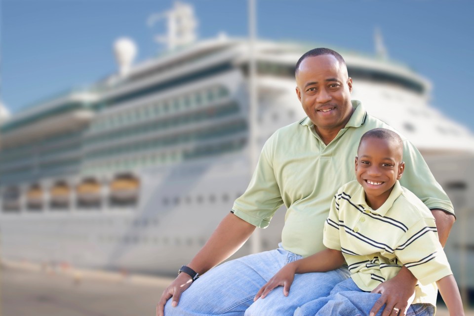 10 tips for traveling with a child with autism Black father and son smiling together in front of cruise ship, representing joyful travel moments with a child with autism – traveling with a child with autism.