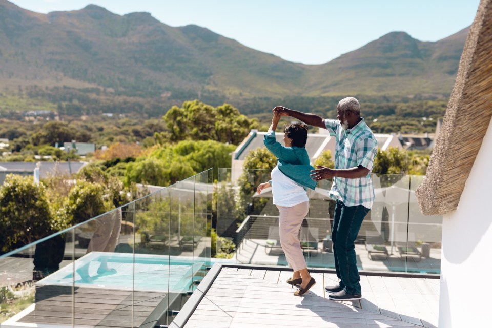 How to create the perfect family vacation home: tips and considerations Happy grandparents enjoying time on the balcony of their family vacation home with scenic mountain views.