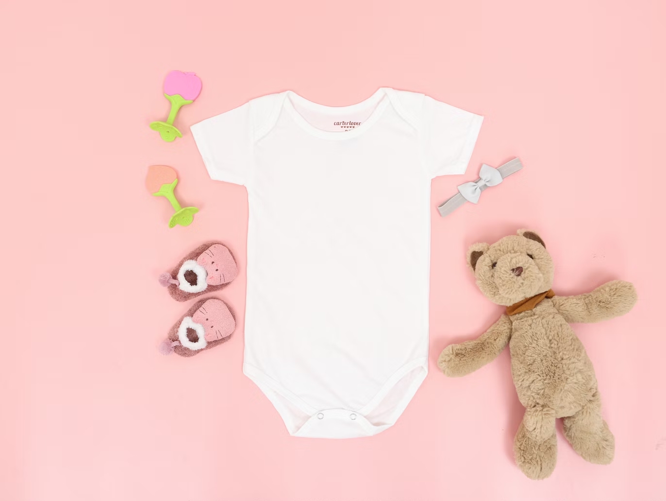 Smart tips for saving money on gently-used baby clothes Gently-used baby clothes on a pink background with a teddy bear for smart tips for parents to save money.
