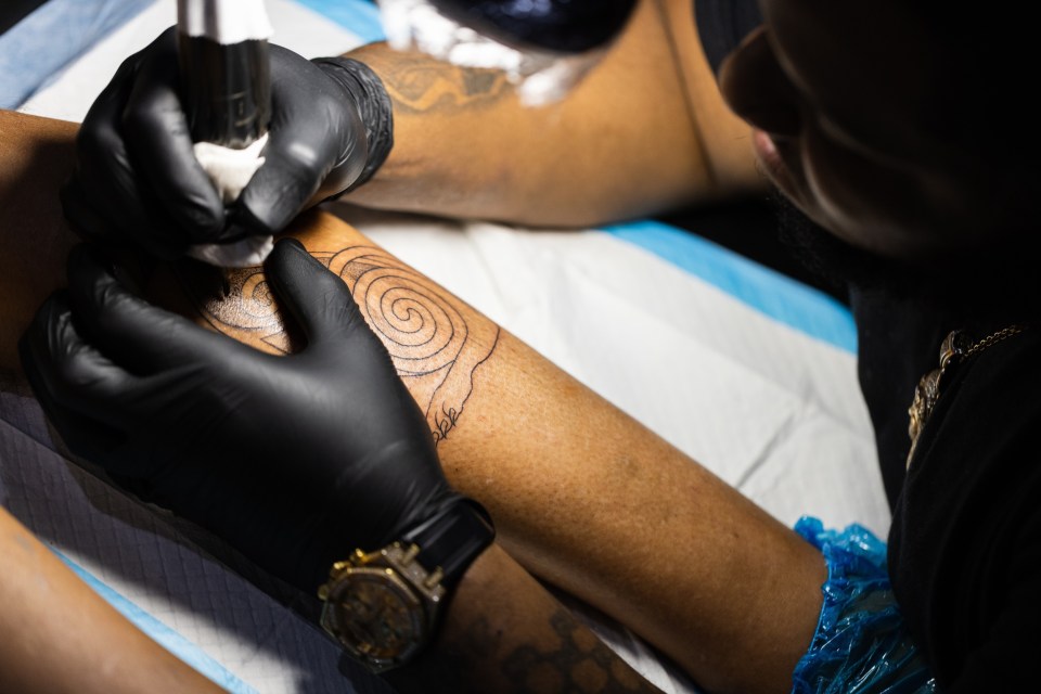 How to discuss tattoos with your adult teen: tips for parents An african american tattoo artist is concentrated on his work. Closeup. For an article titled, how to discuss tattoos with your adult teen: tips for parents