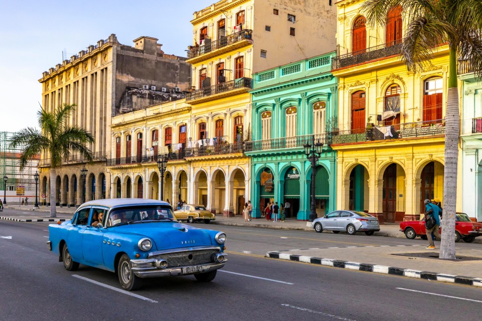 10 breathtaking family-friendly travel destinations worldwide Colorful buildings and a classic blue car on a street in cuba, vibrant family travel spot.
