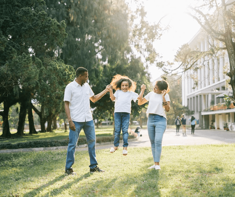 What does 'best interests of the child' mean in family court decisions? Black parents swinging their child joyfully in a sunny park, representing family unity and the importance of child well-being in family court custody decisions.