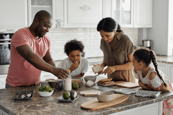 A parent's guide to raising responsible and independent kids An african american family makes breakfast together with their children for an article about a parent's guide to raising responsible and independent kids