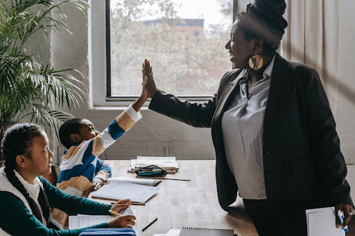 Ai tutors vs. Traditional tutors: exploring the advantages and disadvantages Traditional tutor giving a high-five to a student during a tutoring session, highlighting the personal connection and interactive learning experience, demonstrating the benefits of traditional tutoring compared to ai tutors vs. Traditional methods.